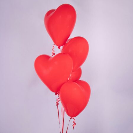 A bunch of red heart-shaped balloons on a white background