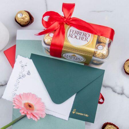 A box of Ferrero Rocher chocolates with a red bow and green envelope