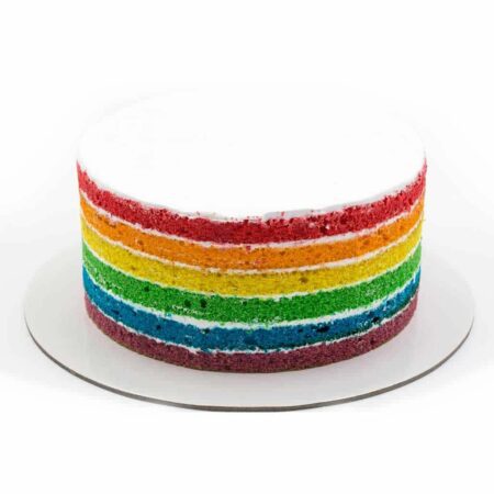 A rainbow cake with white frosting on a white plate