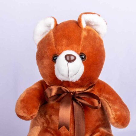A close up view of small brown teddy bear tied with brown ribbon