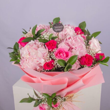 A bouquet of hydrangeas and roses with baby breath in a nice wrapping