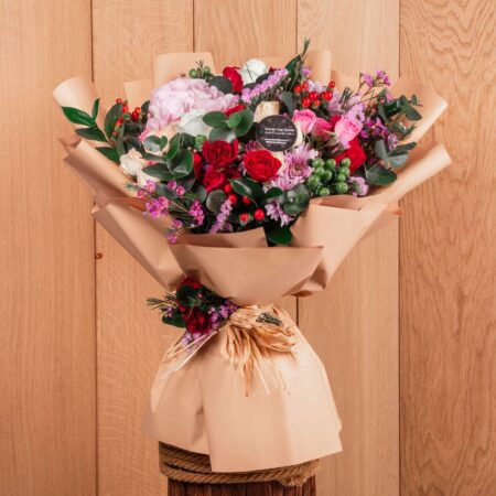 Bouquet of mixed flowers wrapped in brown paper on a wooden table