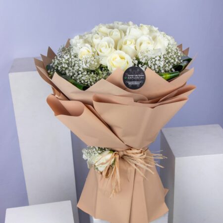 A bouquet of white roses with baby breath wrapped in brown paper