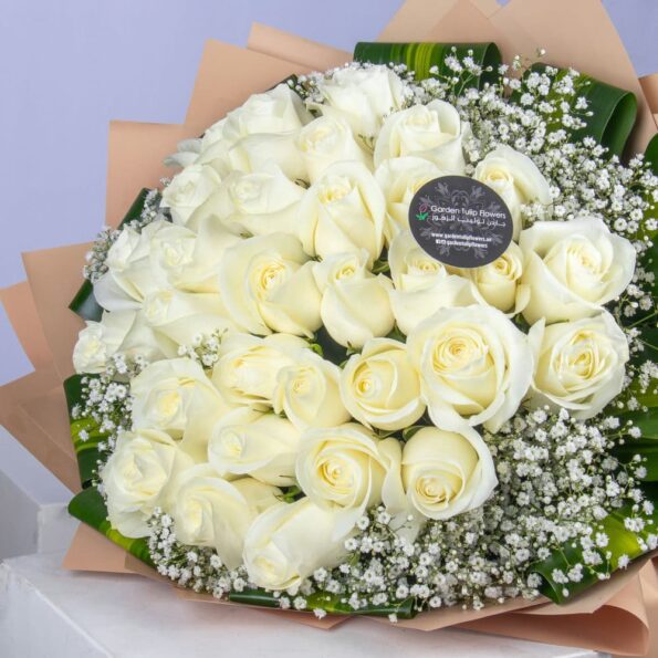 A bouquet of white roses with baby breath wrapped in brown paper