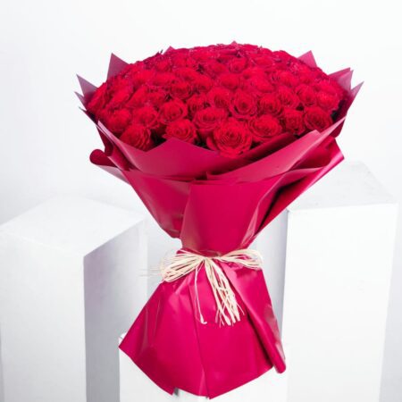 Gift-ready bouquet of 101 premium red roses, elegantly wrapped in rustic red paper and adorned with a natural raffia knot