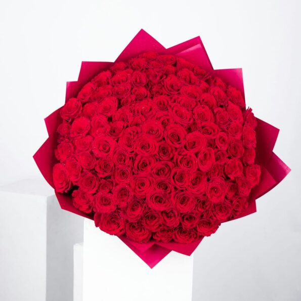 Top view of Gift-ready bouquet of 101 premium red roses, elegantly wrapped in rustic red paper and adorned with a natural raffia knot