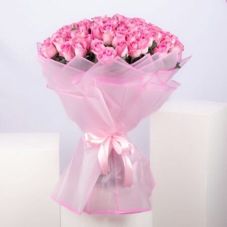 Close-up of a 101 pink rose bouquet, showcasing the vibrant blooms, eco-friendly pink paper wrapping, and delicate pink ribbon
