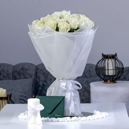 A bouquet of white roses with baby breath and green envelope