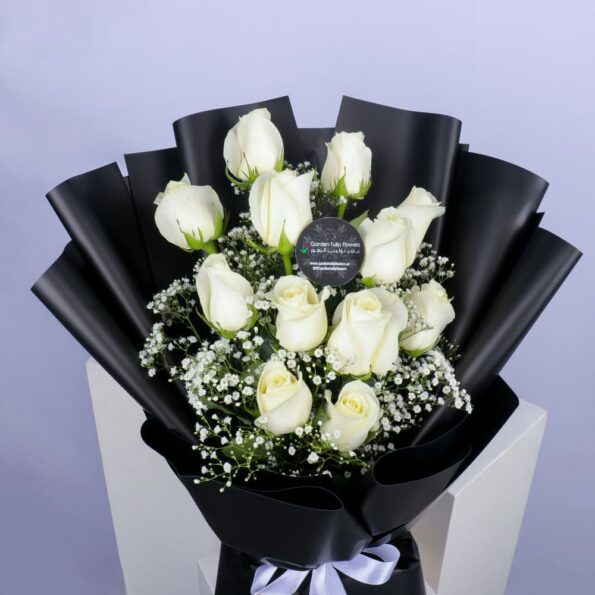 close up of white roses in a black wrapping with a white bow