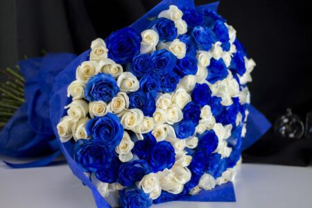 A large bouquet of blue and white roses wrapped in blue
