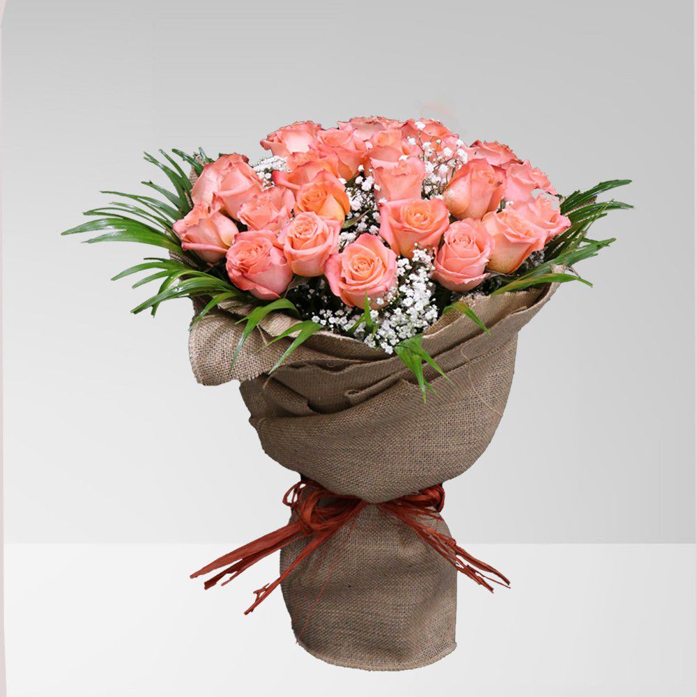 A bouquet of pink roses wrapped in burlap with a red bow