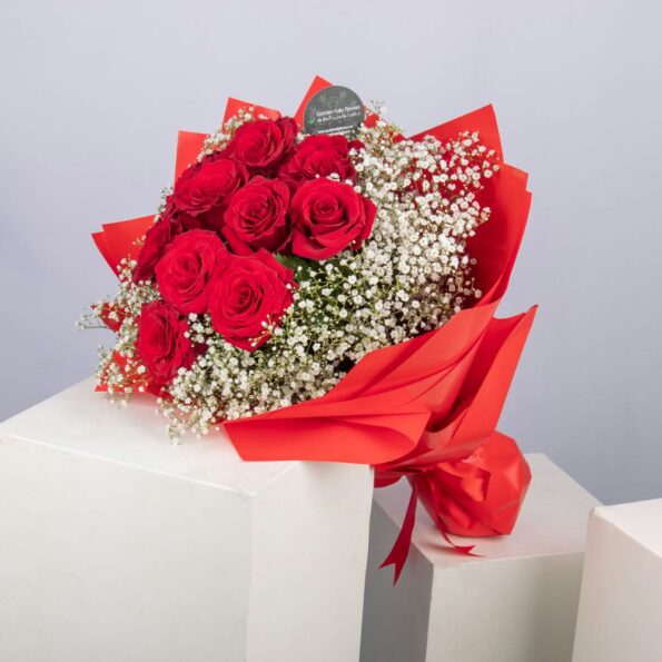 A bouquet of red roses and baby's breath with a box of Ferrero Rocher chocolates