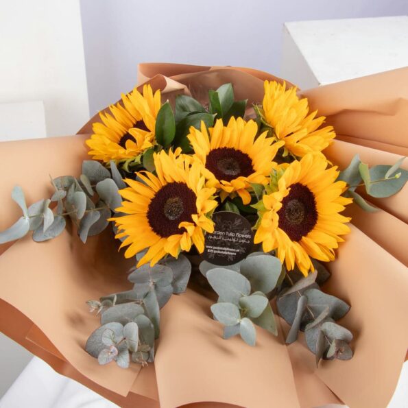 A bouquet of sunflowers wrapped in brown paper