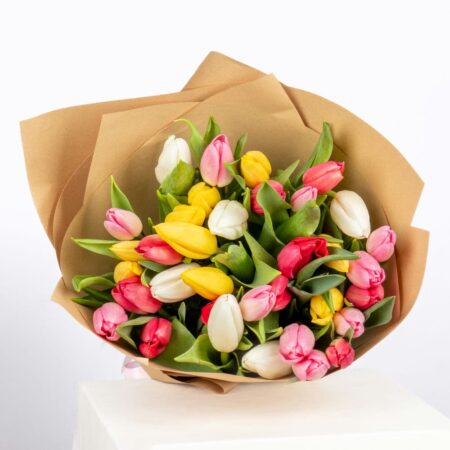 Top view of a mixed-color tulip bouquet, highlighting the various shades and eco-friendly brown paper wrapping
