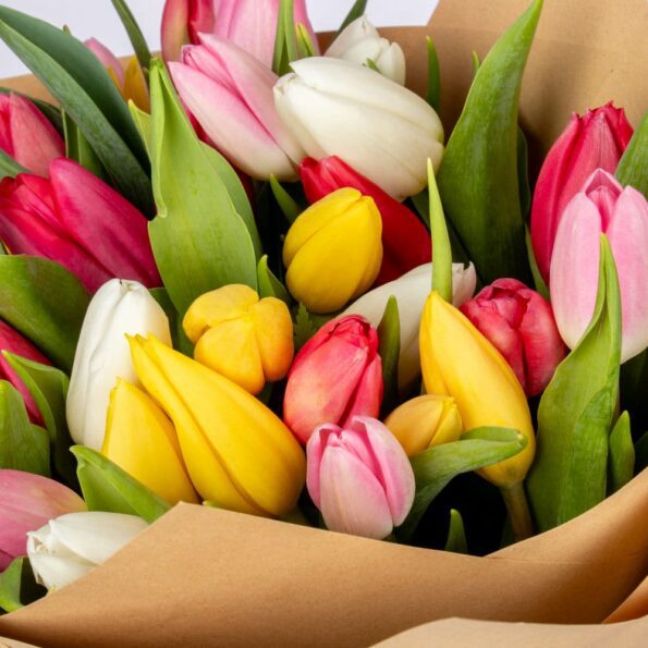 Close-up of a mixed-color tulip bouquet, highlighting the various shades and eco-friendly brown paper wrapping