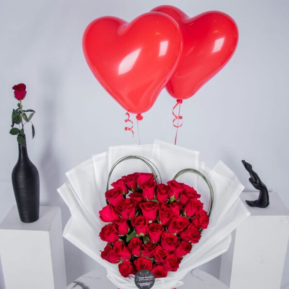 Red roses arranged in heart shape with heart shaped balloons