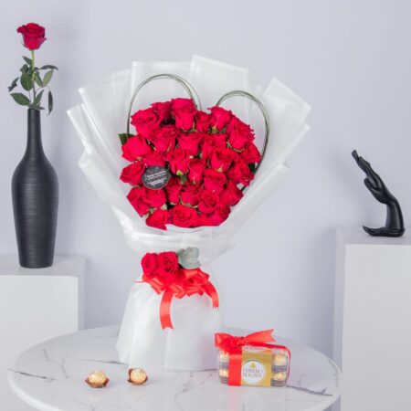 Red roses arranged in heart shape bouquet with chocolates