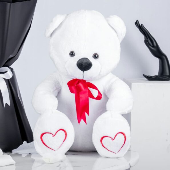 White teddy bear tied with red ribbon