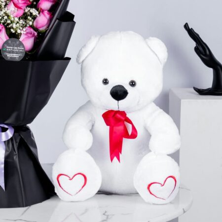A bouquet of pink roses in a nice black wrapping with teddy bear