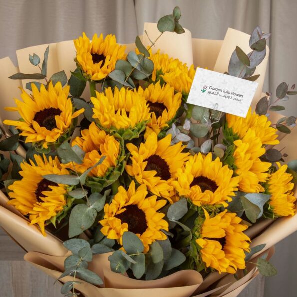 A bouquet of sunflowers wrapped in brown paper with a card
