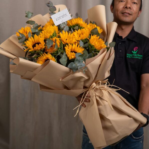A bouquet of sunflowers wrapped in brown paper with a card