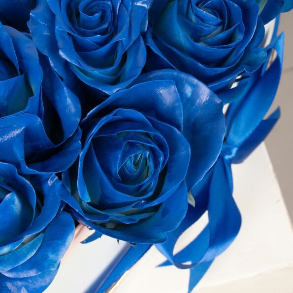 close-up view of Blue roses arranged in heart shaped white box