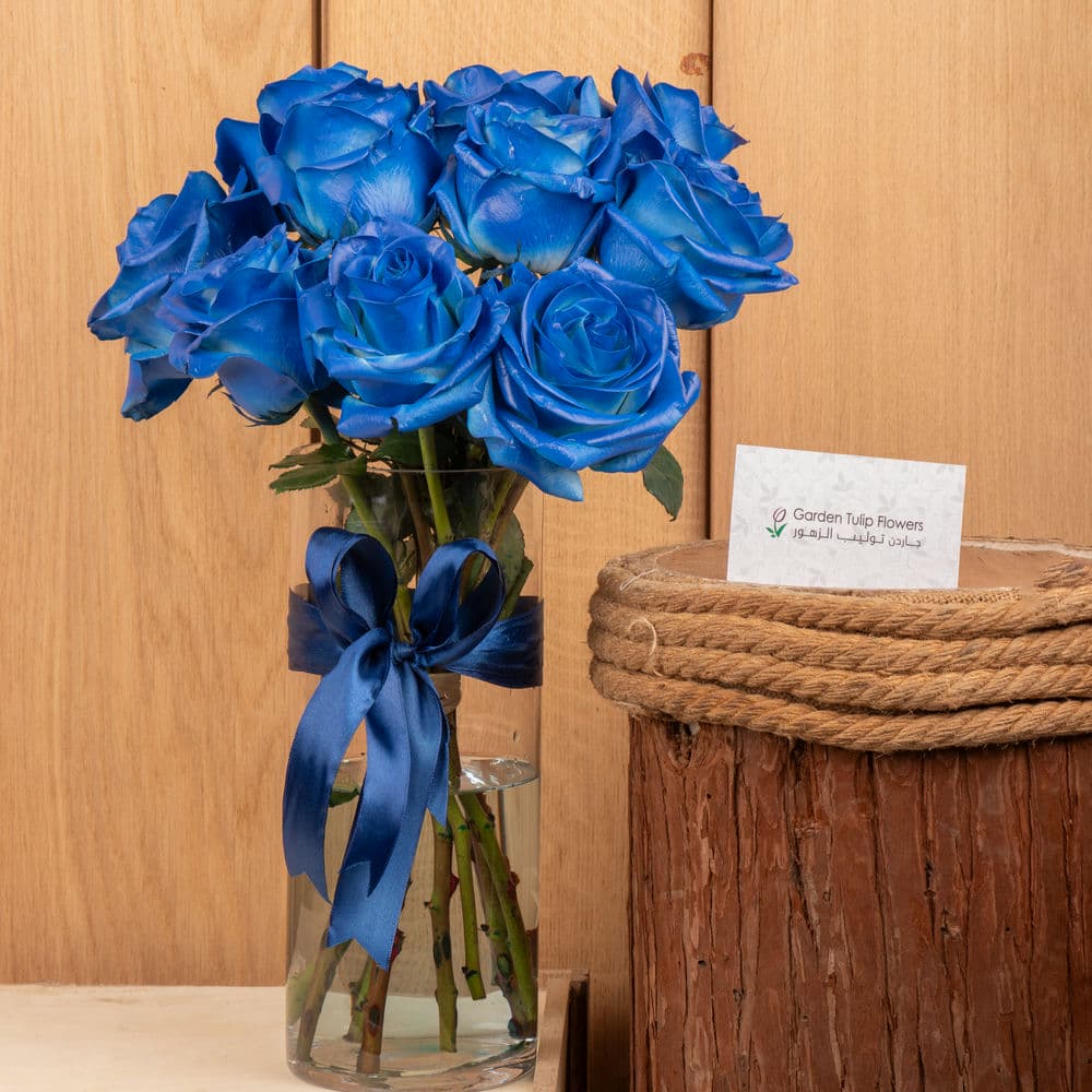 A vase of blue roses with a blue ribbon